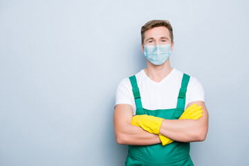 Portrait of confident janitor wearing blue face mask standing with folded arms isolated on gray...