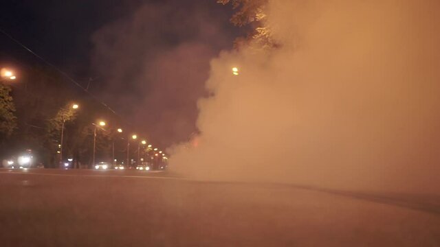 Car start with smoke on wheels. Footage. Red modern drag sport auto burning tire at city street.