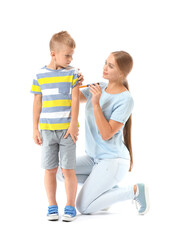 Mother giving her diabetic son insulin injection on white background