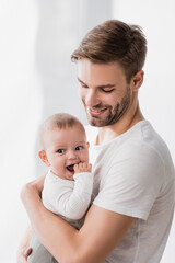 happy father holding in arms baby boy sucking fingers