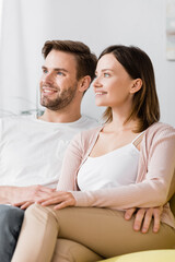 cheerful man and woman sitting on sofa at home