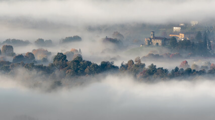 Italian town wrapped by mist at dawn, Lombardy