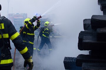 Firefighters with breathing apparatus intervene in the smoke during a fire on old railway sleepers
