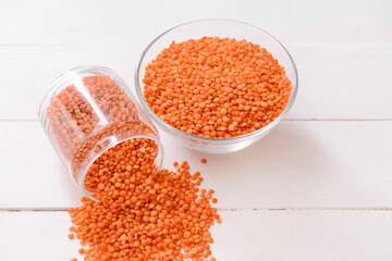 Bowl and jar with raw lentils on white wooden table