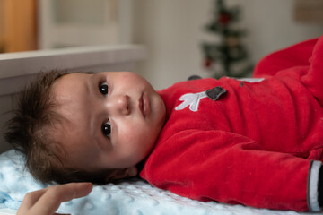 Closeup portrait of newborn baby. baby in Santa costume lying around the bright lights at the Christmas tree in new year's eve