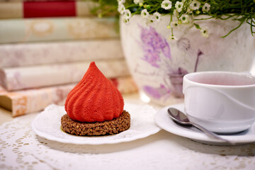 Velvet red cake with tea on the table with flowers and books.