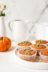 Plate with tasty pumpkin muffins on table