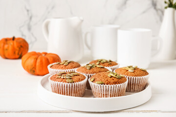 Plate with tasty pumpkin muffins on table
