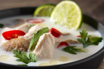 Traditional Thai food Tom Kha Gai in bowl on wooden table. Close up	