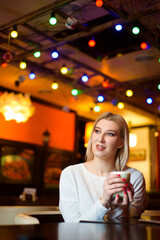 Winter girl is drinking coffee. She enjoys her cappuccino or flat white.