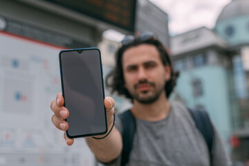 A man with a phone in his hand near the schedule at the station