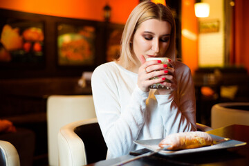 Beautiful woman drinking coffee at the cafe wintertime.
