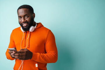 Cheerful african american man with headphones using cellphone