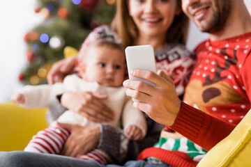 man taking selfie with wife and baby son on blurred background