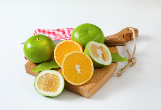Green grapefruits and halved orange