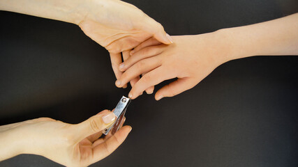 Mom cuts her child's nails. Close up and black background