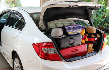 Closeup of rear side of white car carrying suitcases and things.