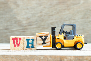 Toy forklift hold letter block y to complete word why on wood background