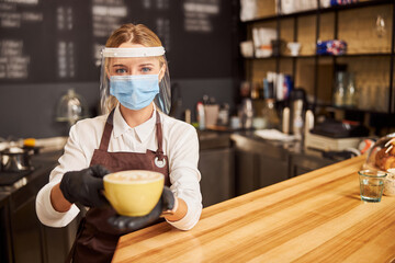 Pretty barista with cup of hot cappuccino in hands