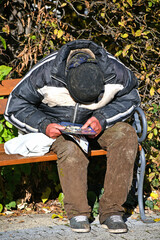 Homeless man sits on a park bench