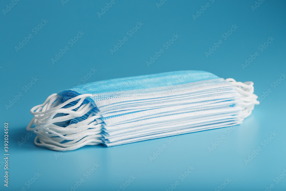 Wall mural Stack of protective medical masks on a blue background, isolate.