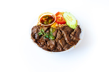 Asian dish prepared with beef pieces, tomatoes and cucumber slices on top of fried rice served in a bowl, for an healthy and complete meal