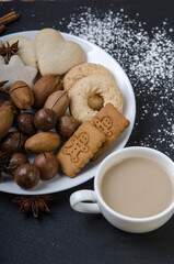 Bowl with gingerbread walnuts and a cup of cocoa on a black top