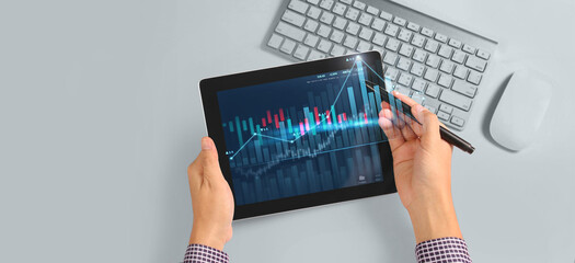 Hand holding tablet and showing holographic graphs stock market statistics gain profits