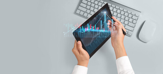 Hand holding tablet and showing holographic graphs stock market statistics gain profits