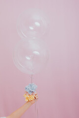 female hand holding balloons. studio photo with pink background.