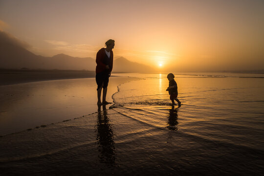 Silhouette of young mother son walking on reflected beach in Cofete, Fuerteventura, Canary Islands, Spain.