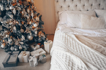 Decorated Christmas tree with gifts in white classic New Year's bedroom holiday interior