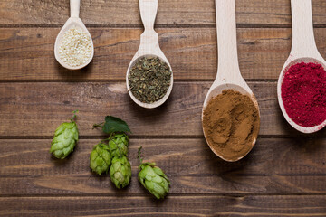Spices in spoons on wooden table with hop