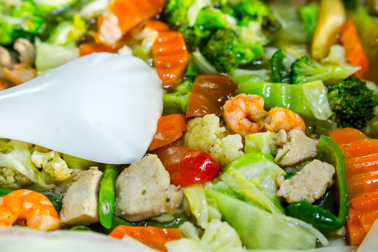 Closeup of Chop Suey with shrimp, broccoli, bell peppers, carrots, string beans and chicken bits.