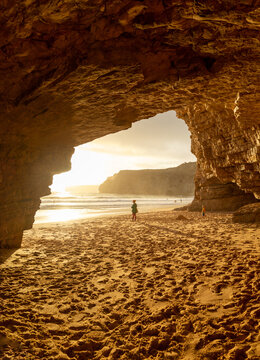 Mother and son in large cave on beach in Algave in Portugal.