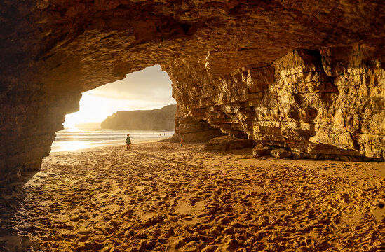 Mother and son in large cave on beach in Algave in Portugal.