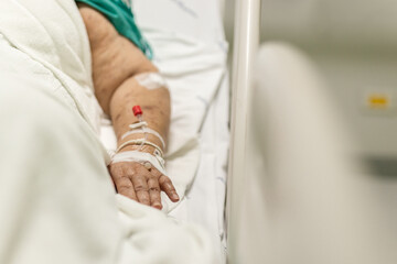 Old woman lying in bed with saline solution in hospital.