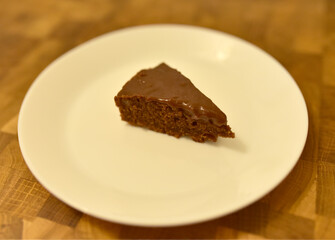 Brown Sugar Chocolate Cake on a white plate on the background of a wooden table in a restaurant. Sweet food concept