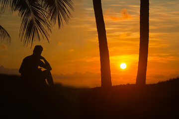 A man sitting and waiting to watching the sunrise on the coconut beach in the morning
