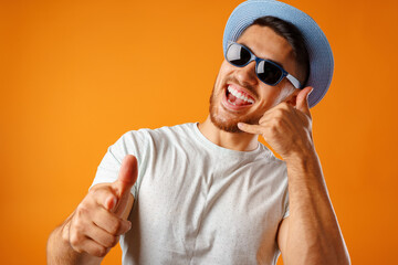 Overjoyed man in straw hat and sunglasses showing call me gesture