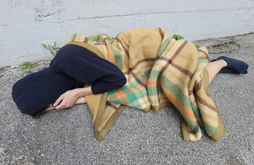 homeless as he sleeps on the floor under a filthy blanket and ho
