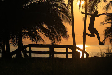 Men running and jumping for morning exercises at sunrise on a coconut beach