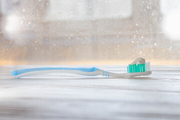 Turquoise, blue toothbrush with white toothpaste on the bristles on a white wooden background. Copy...