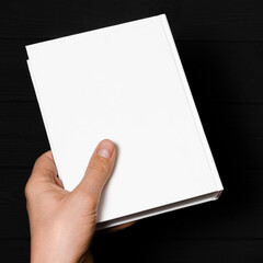 A mock-up of a white closed book with a place for text in a hand