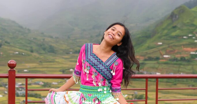Cheerful beautiful Asian girl in a colorful cultural dress dancing and smiling.