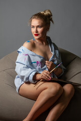 girl artist with brushes in a shirt stained with paints.