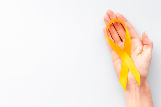 Yellow Cancer Awareness Ribbon In Hand. Top View