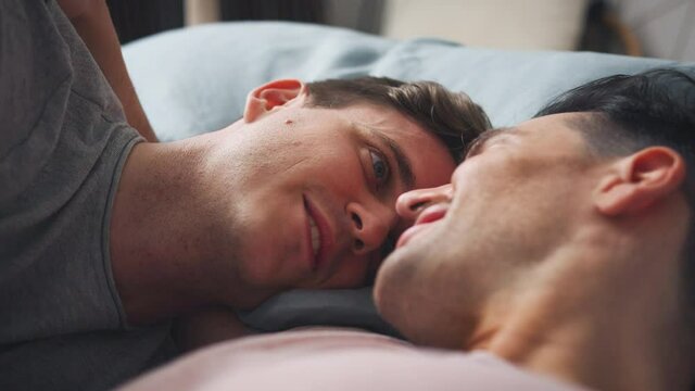 Close up shot of loving same sex male couple lying on bed at home and kissing - shot in slow motion