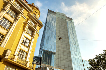 Perspective view of modern high-rise glass skyscraper and old buildings in city center.