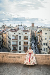 Woman with the traditional costume of the Fallas of Valencia. Woman leaning on a Moor enjoying the sunset in the old city of Valencia.